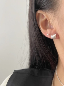 Close-up of 925 sterling silver textured heart earring and ball stud on ear