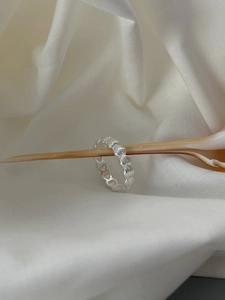 Detailed view of silver minimalist ring with textured beads over seashell background