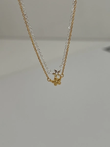 Détail de colliers avec pendentifs fleurs minimalistes en argent et or sur chaînes fines