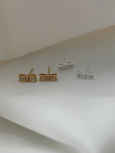Détail de boucles d'oreilles nœuds en argent avec cristaux brillants sur satin blanc