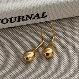 Polished gold teardrop earrings in 925 sterling silver on a grey textured background
