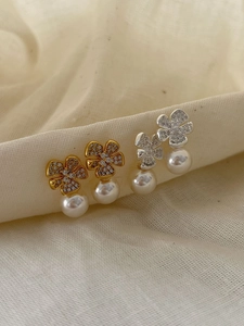 Close-up of pearl drop earrings with sparkling clover zircon and gold silver finish