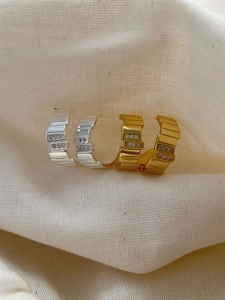 Close-up of C-shaped silver and gold hoop earrings with double-row micro zircons