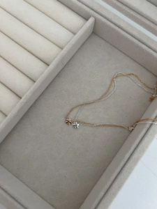 Gros plan sur un collier double couche minimaliste avec pendentifs fleurs en or et argent