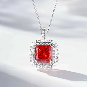 Macro shot of rectangular orange gemstone pendant with diamond halo on silver chain
