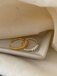 Detailansicht verstellbarer Spiralringe in Silber und Gold auf Keramiktablett