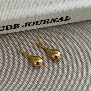 Elegant gold waterdrop earrings with polished finish on a textured minimalist background
