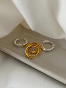 Detailed close-up of 925 silver twist hoops in gold and silver finish on a ceramic tray