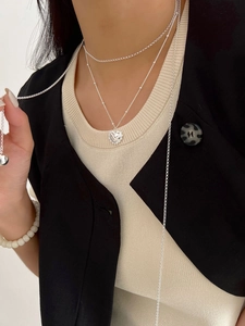 Détail du collier à plusieurs rangs en argent avec pendentif coeur gravé de la lettre V