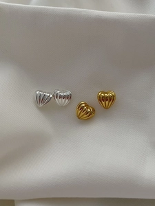 Macro detail of 925 sterling silver heart studs with textured vertical ridge patterns