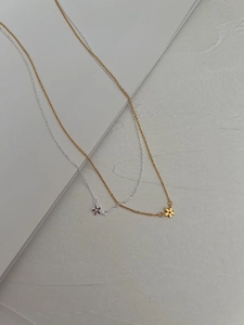 Gros plan de mini colliers avec pendentif fleur en argent 925 en versions or et argent
