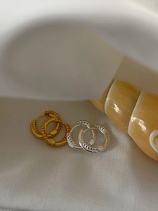 Detailed shot of twisted 925 silver hoop earrings in gold and silver on a white fabric