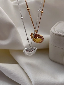 Détails de pendentifs en forme de cœur dorés et argentés sur un tissu en soie
