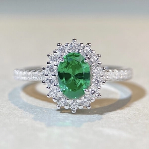 Détail macro d'une bague pierre verte ovale avec monture halo et anneau en pavé