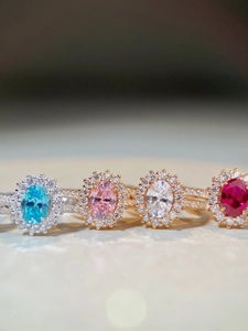 Close-up of four silver and rose gold rings with colorful oval-cut gemstones and diamonds
