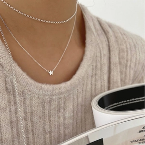 Collier minimaliste en argent 925 avec pendentif fleur sur un pull en maille fine