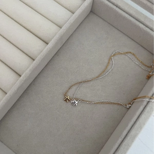 Ensemble collier fleur en argent 925 doré et argenté présenté sur un plateau en velours