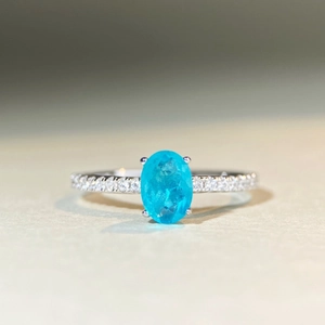 Macro shot of oval blue gemstone ring with micro-paved band in silver setting