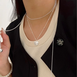 Collier multi-rangs avec pendentif cœur texturé porté par un mannequin en costume