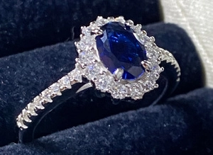 Macro view of a deep blue oval sapphire halo ring in a premium blue velvet jewelry gift box