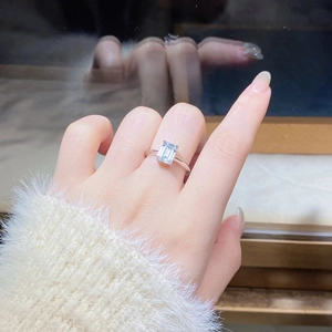 Close-up of emerald cut moissanite ring in 925 silver worn on a woman's finger
