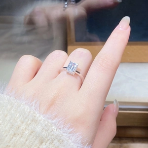 Macro shot of the emerald-cut moissanite ring set in 925 sterling silver on a finger
