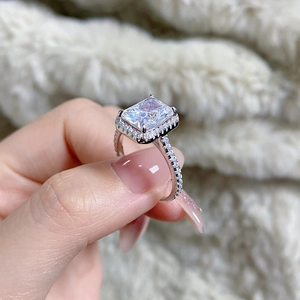 Detailed view of Radiant cut silver ring with halo setting on a person's hand