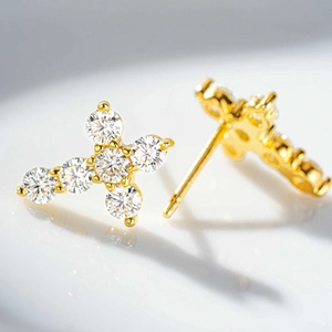 Macro shot of gold cross stud earrings featuring brilliant round-cut moissanite stones