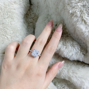 Close-up of radiant cut engagement ring with halo setting and pavé band on white fur