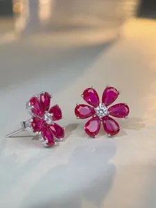 Macro shot of S925 silver stud earrings featuring red ruby petals and a diamond center