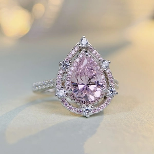 Macro view of pear-cut pink crystal ring with sparkling halo and silver band details