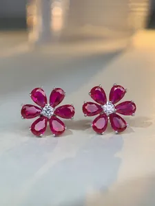 Macro view of S925 silver flower stud earrings with red pear-cut ruby petals and diamond core