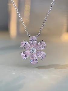 Macro shot of silver flower pendant necklace with pink pear-cut petals and white center stone
