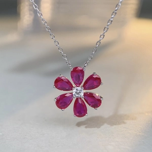 Vue macro d'un pendentif fleur avec pierres rouges en forme de poire et chaîne argent