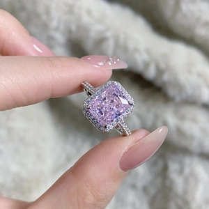 Macro view of a luxury radiant cut pink gemstone ring with halo diamond setting on hand