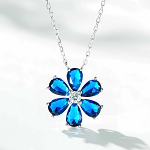Détail macro d'un pendentif fleur en argent 925 avec pétales bleus et zircon blanc pur