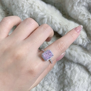 Close-up of radiant pink rectangular cut diamond ring on model hand with velvet background