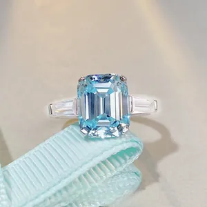 Macro shot of 6 carat emerald cut aquamarine ring with side diamonds on blue ribbon