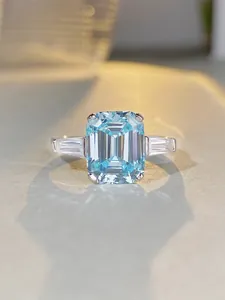 Macro detail of a 925 sterling silver ring with emerald-cut blue gemstone and side stones