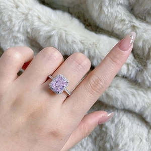 Macro shot of halo set pink radiant cut gemstone ring with diamond pavé band