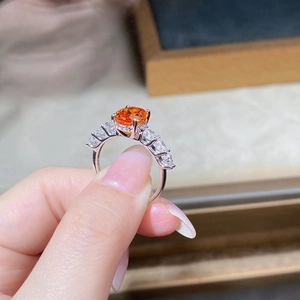 Macro shot of 3ct oval orange gemstone ring with sparkling side stones on a silver band