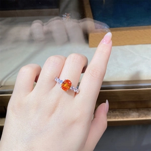 Macro detail of a 3-carat orange oval gemstone ring with diamond accents on S925 silver band