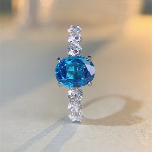Detail of oval blue gemstone and small white zircons set on silver ring band