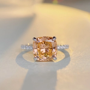 Cushion-cut champagne orange gemstone ring with silver pave band on a textured background