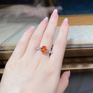 Macro detail of silver ring with 3-carat oval orange gemstone and diamond accents