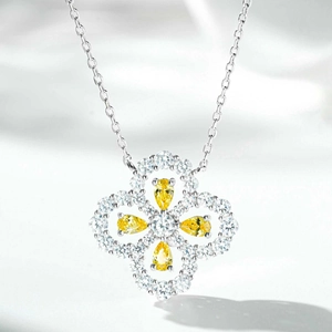 Macro shot of silver four-leaf clover pendant with pear-cut yellow crystals and diamonds
