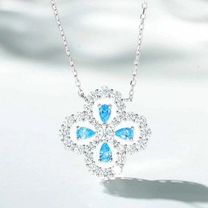 Macro detail of silver four-leaf clover pendant with blue stones and pave crystals