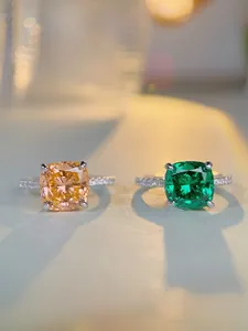 Detail of cushion-cut champagne and emerald green gemstones with pavé-set silver rings