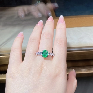 Gros plan d'une bague émeraude 3 carats avec pavé de diamants sur anneau en argent