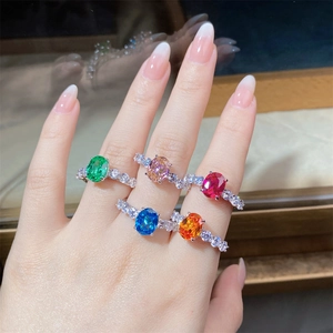Close-up of assorted oval zircon rings in various colors on hand with silver diamond bands